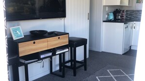 A modern kitchen with a black countertop, white cabinets, and a large flat-screen TV mounted above the counter. - Modern Bach with a Rural view (Riverton)