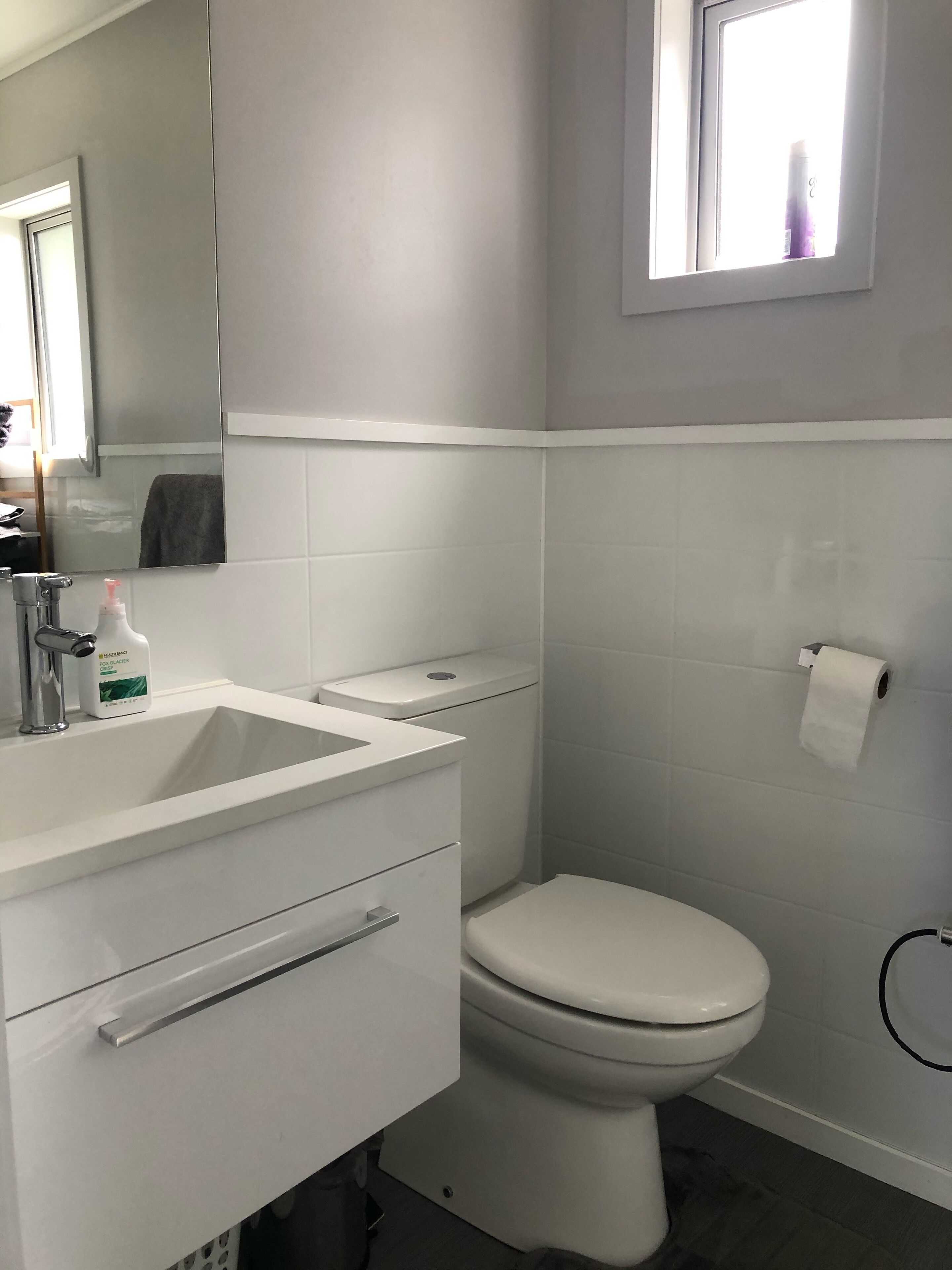 A modern bathroom with a white sink, toilet, and mirror.