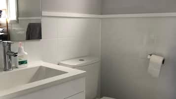 A modern bathroom with a white sink, toilet, and mirror.