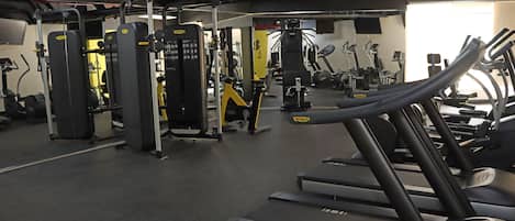 Un gimnasio con cintas de correr, máquinas de pesas y equipamiento de ejercicio.