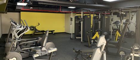 Une salle de sport équipée de divers appareils d’exercice, notamment des tapis de course, des appareils de musculation et des poids libres.