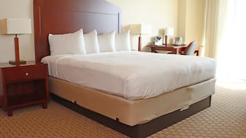 Una habitación de hotel con una cama grande, una mesita de noche, un escritorio y una silla.
