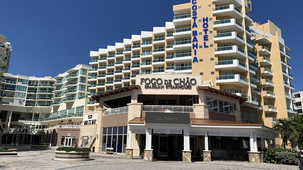 Um hotel de vários andares com varandas, uma entrada central e um letreiro para 'Fogo de Chão Brazilian Steakhouse'.