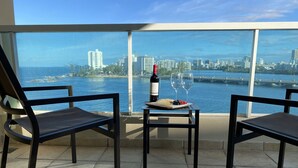 Uma varanda com duas cadeiras, uma mesa, uma garrafa de vinho e um copo de vinho.