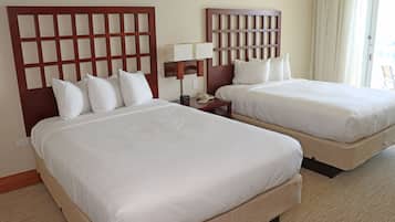 Una habitación de hotel con dos camas, una mesita de noche con lámpara y un teléfono.