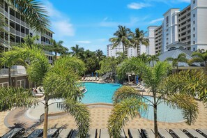 A hotel with a pool surrounded by palm trees and lounge chairs. - Regatta - Tropical Waterfall Pool View (Naples)