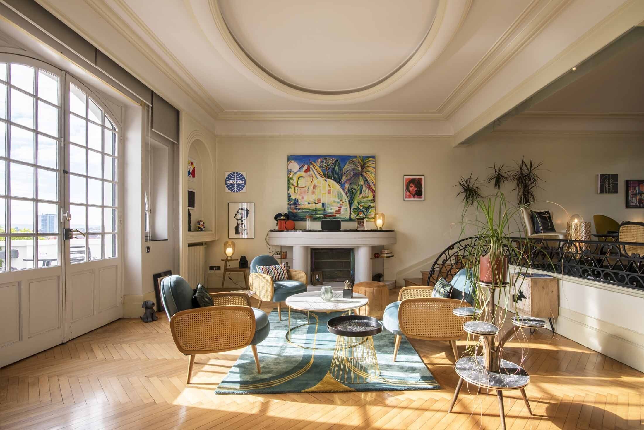 Un salon spacieux doté d’une cheminée, de grandes fenêtres et de différents types de sièges.