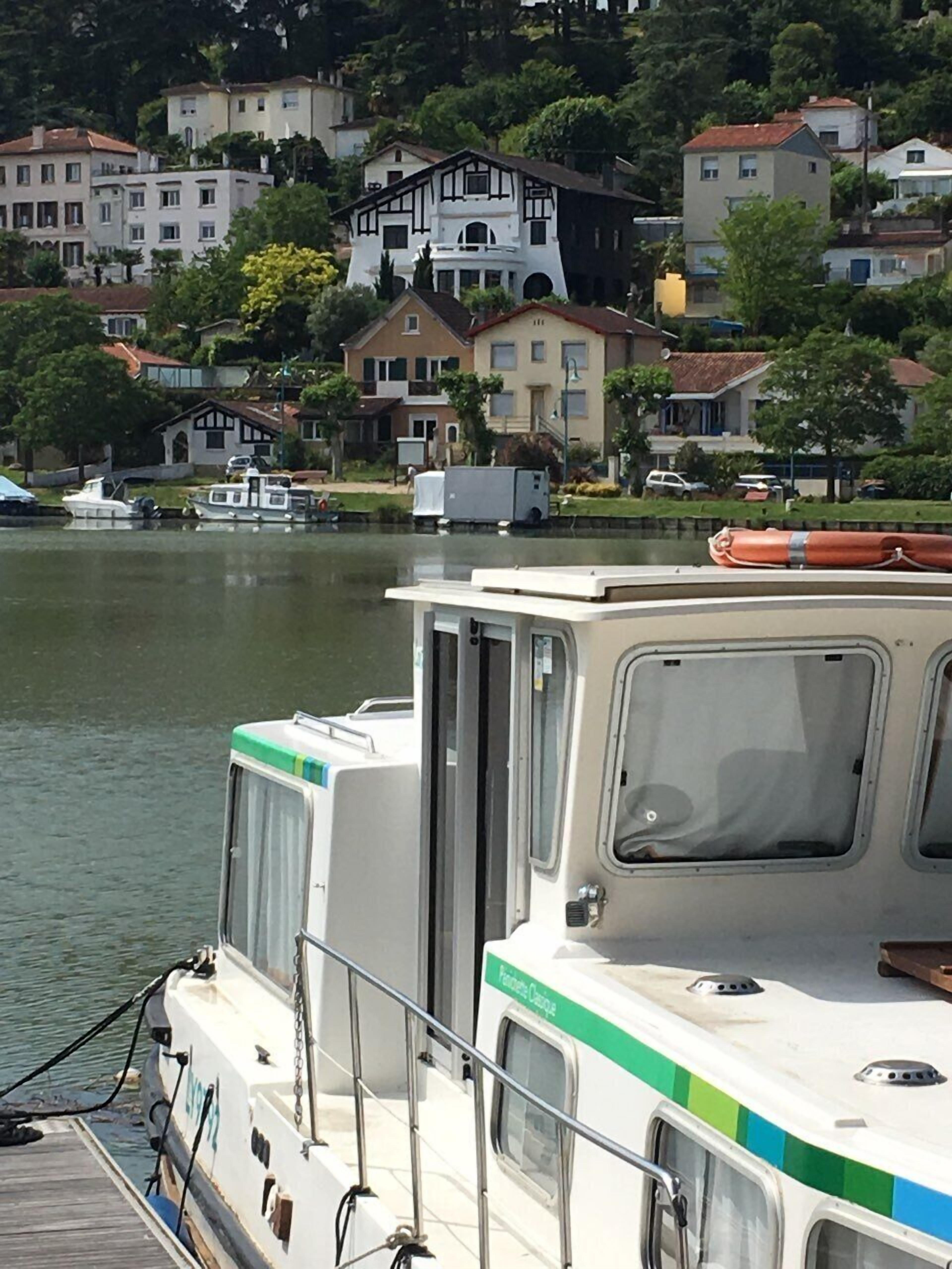 Un barco amarrado cerca de la orilla, con casas al fondo.