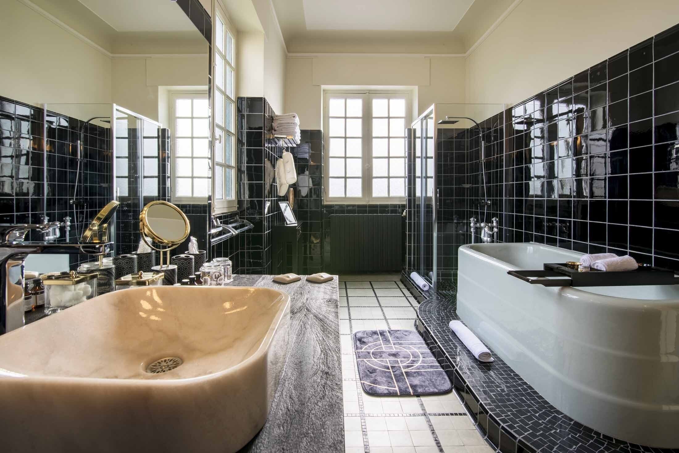 A spacious bathroom with a large beige sink, a freestanding bathtub, and a vanity with a mirror and toiletries.