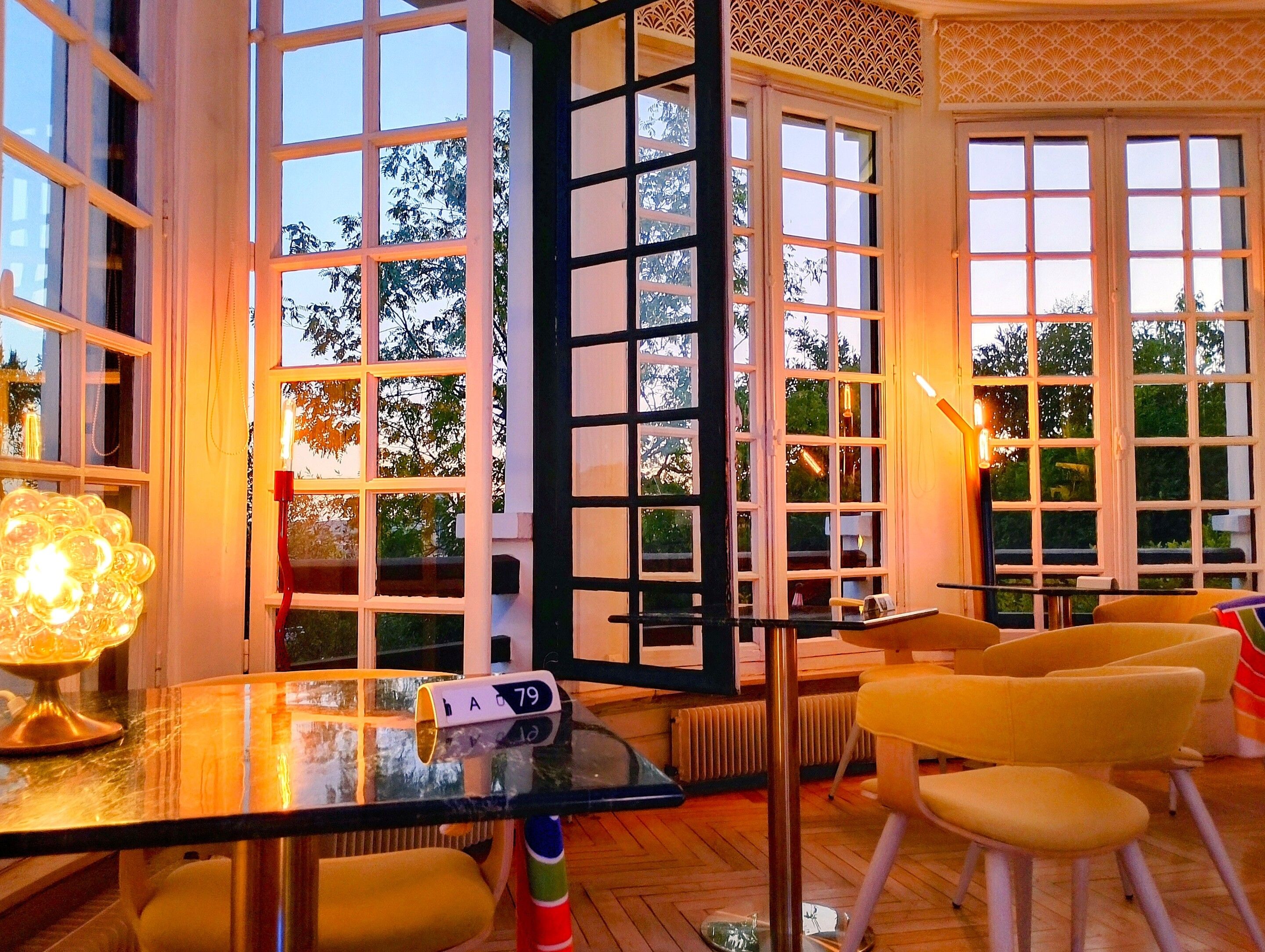 A room with large windows, a glass table, and yellow chairs.