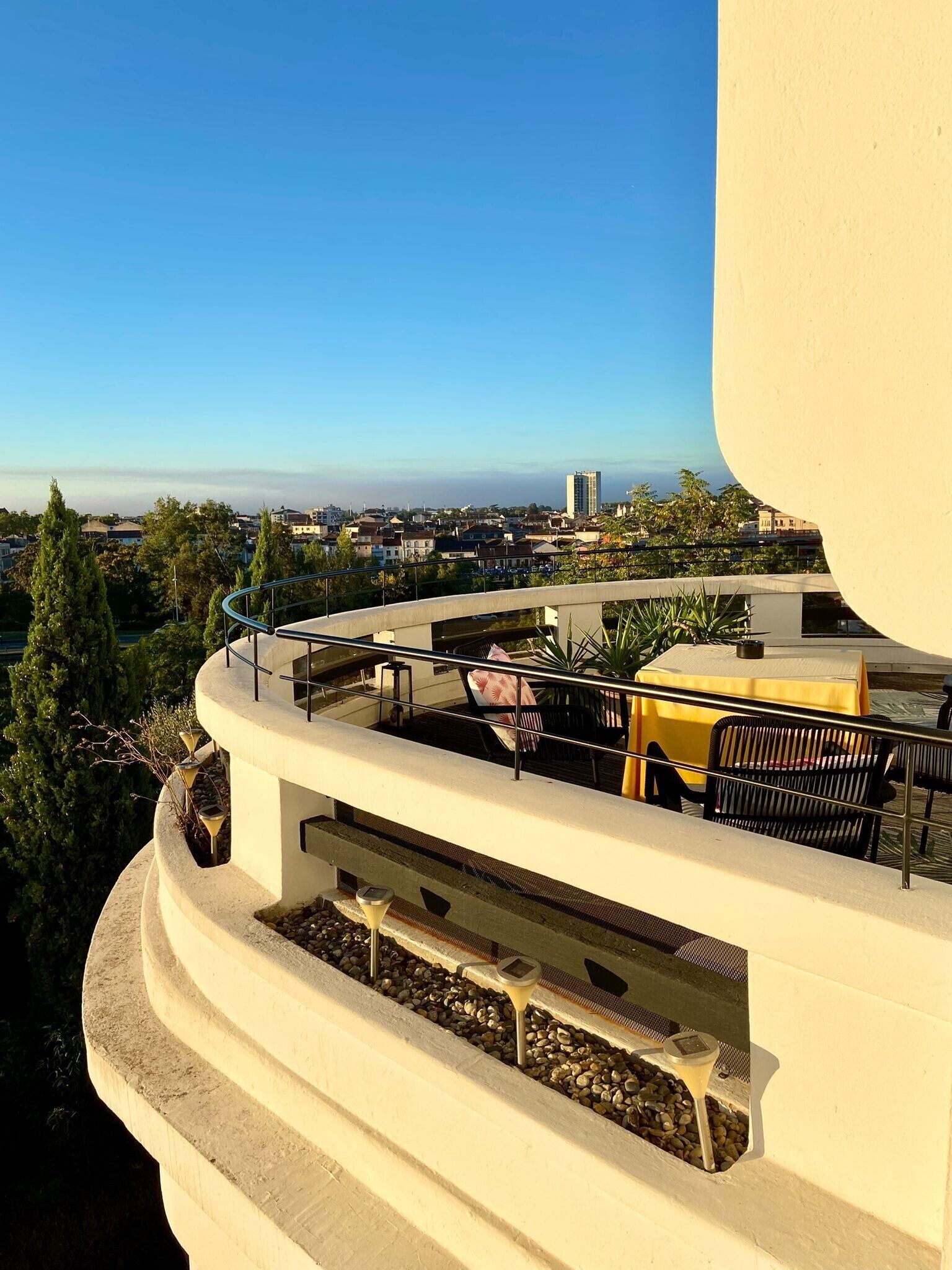Terraço no telhado com área de estar ao ar livre, vista da cidade e um edifício ao fundo.