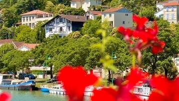 A coastal village with traditional houses, a marina with boats, and lush greenery.