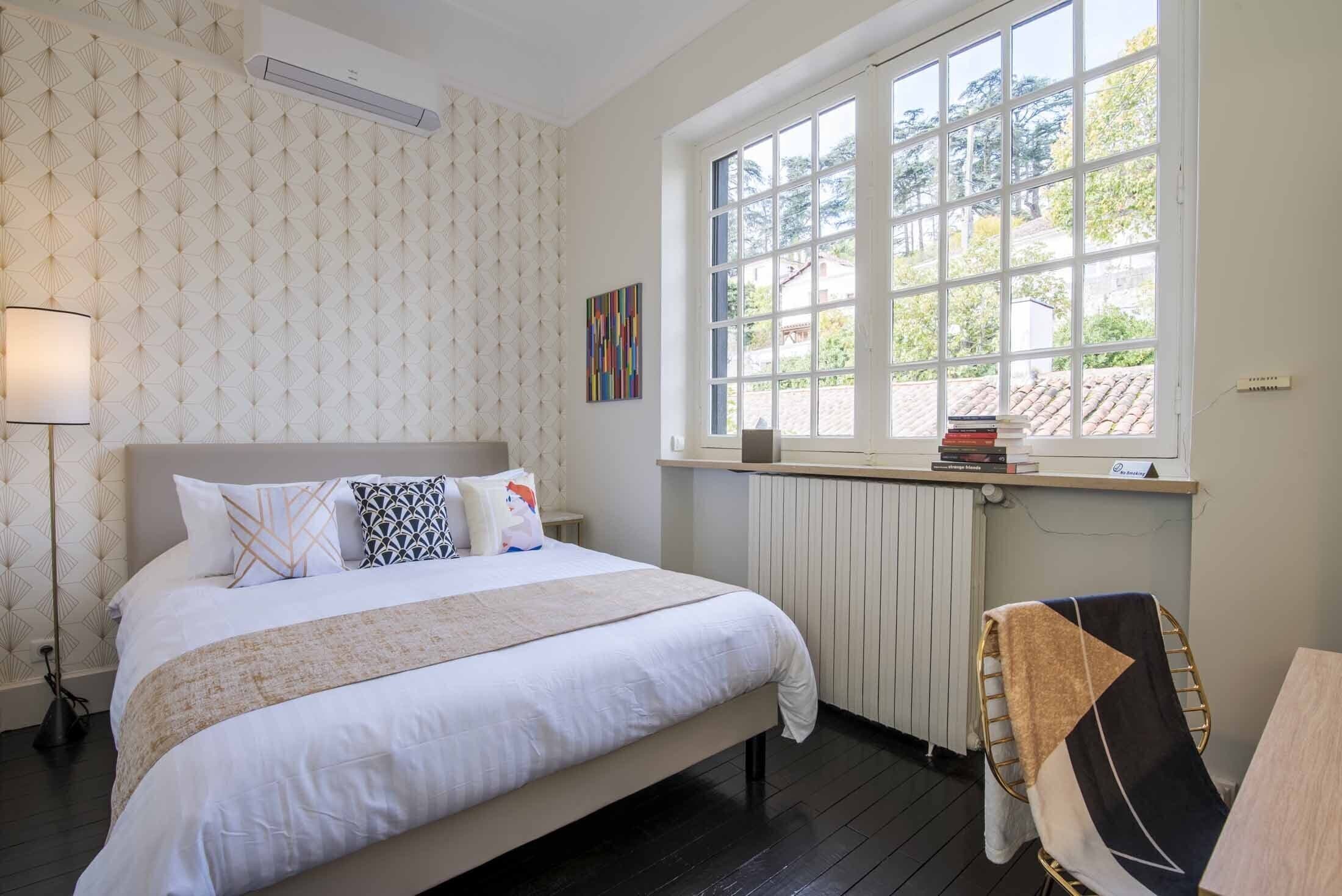 Un dormitorio ordenado con una cama grande, una ventana con vistas y un radiador.