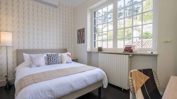 Un dormitorio ordenado con una cama grande, una ventana con vistas y un radiador.