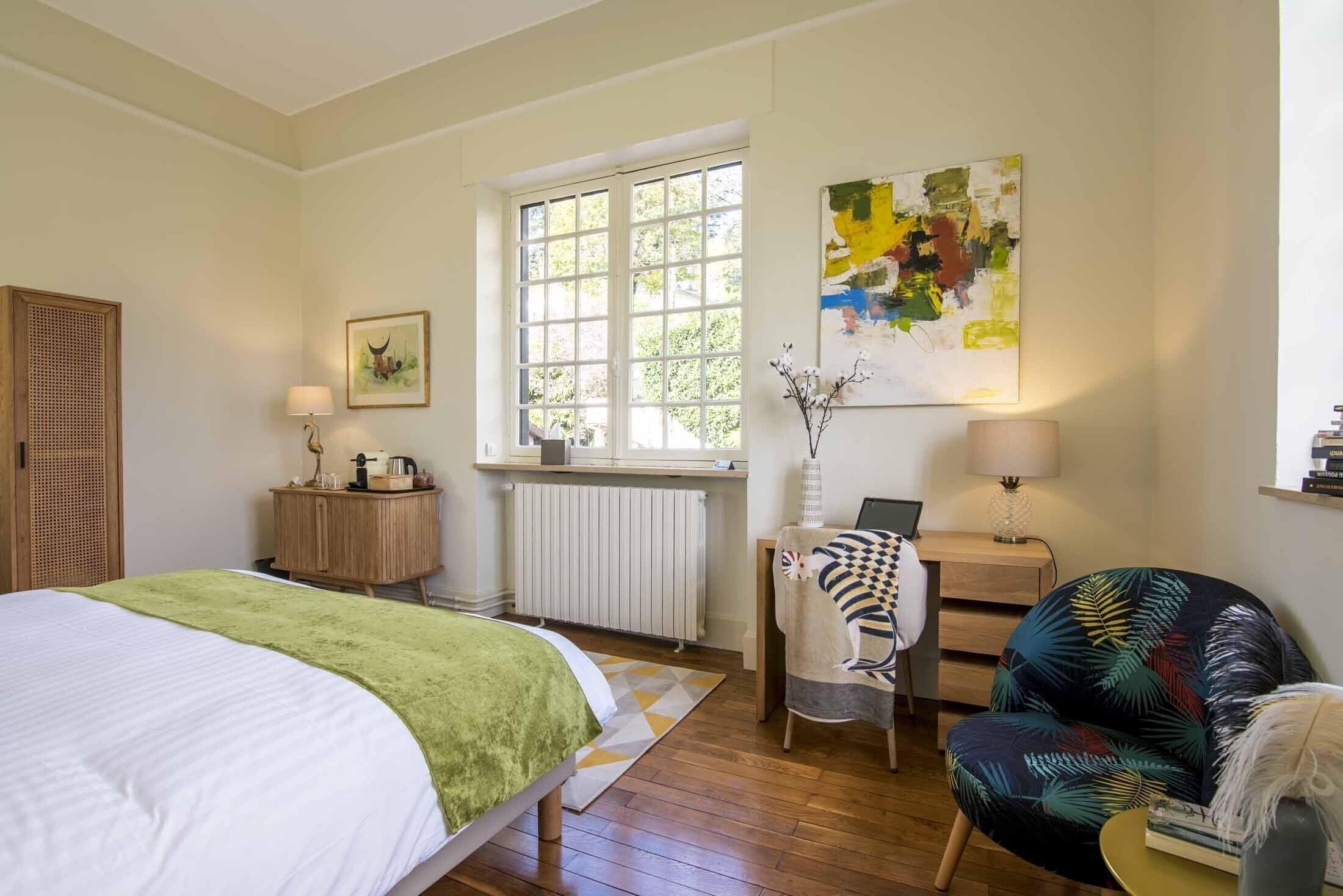 Ein Schlafzimmer mit Bett, Fenster, Schreibtisch, Stuhl und einem Bild an der Wand.
