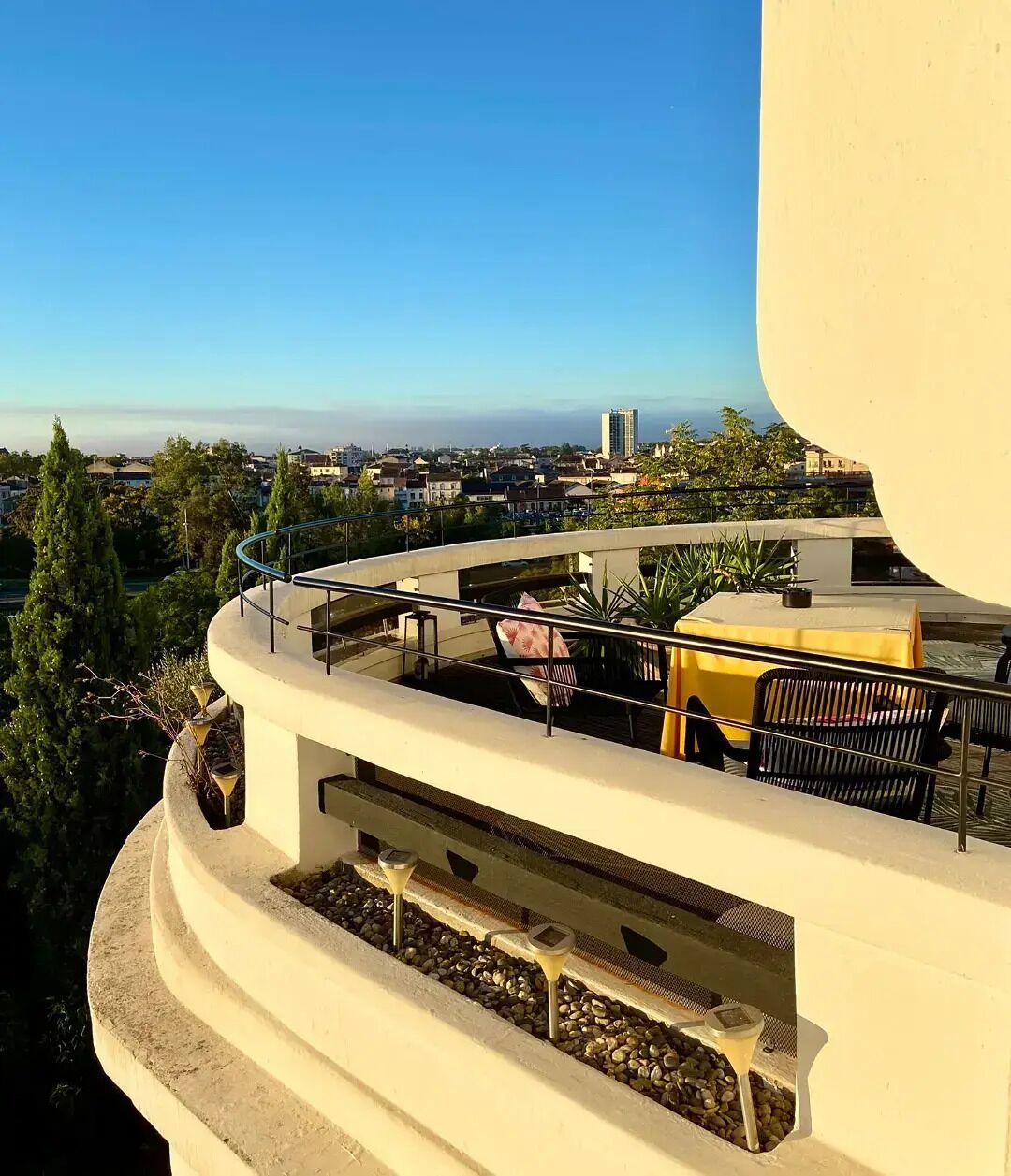 A balcony with a view of a cityscape, including buildings and trees.