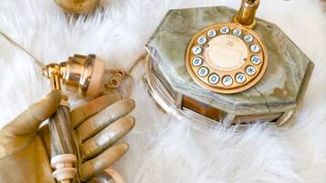 A hand holding a metallic object with a cylindrical shape and a knob, a hexagonal object with a circular dial, and a decorative item with a chain.