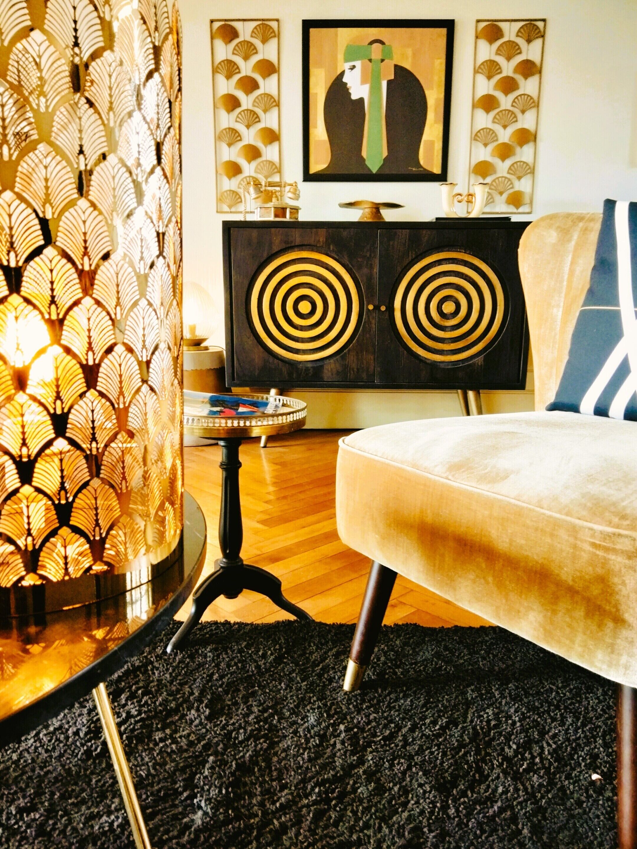 A modern living room with a patterned wall, a vintage-style sofa, a decorative cabinet, and a framed artwork on the wall.