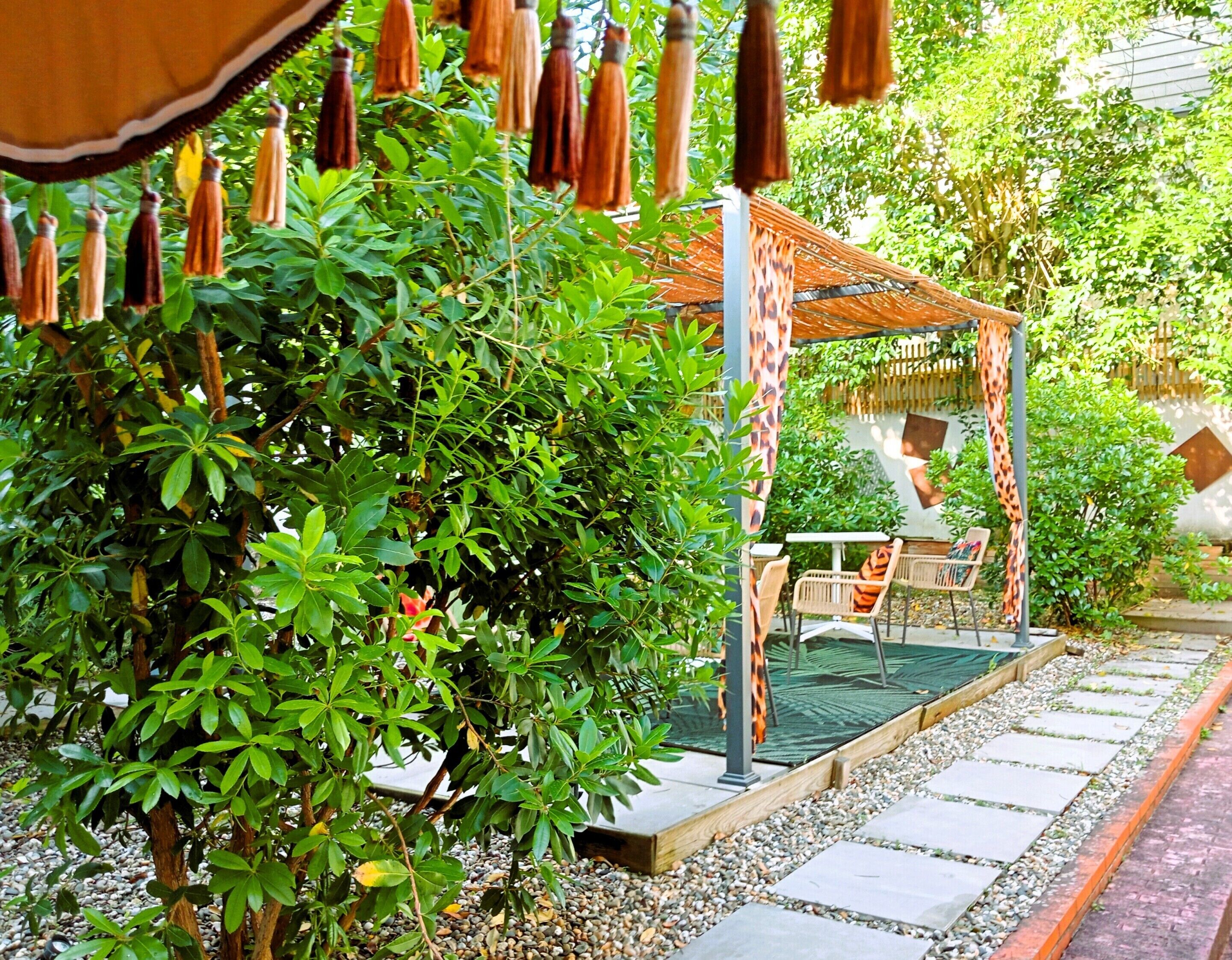 A garden with a pergola, seating area, and a pathway.