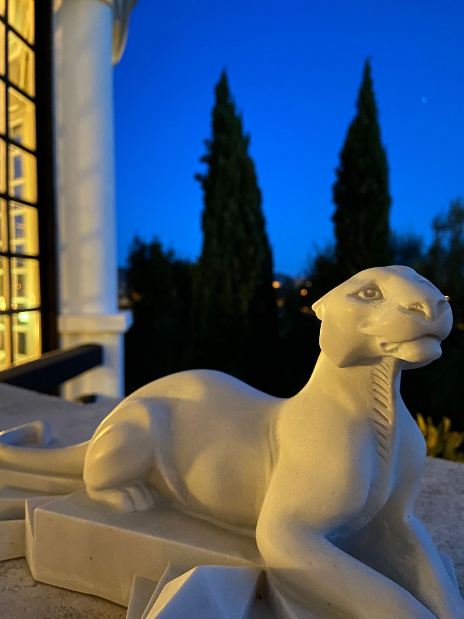 Una escultura de piedra blanca de un león en un jardín.