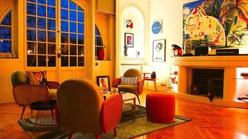 A spacious living room with a large window, a fireplace, and various artworks.