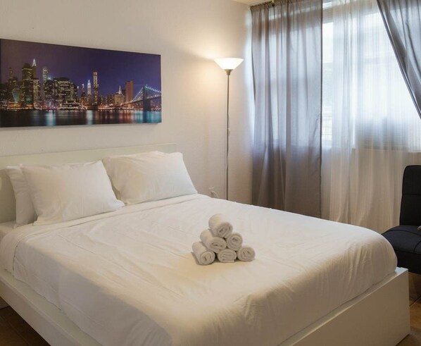 A neatly made bed with white linens and a pile of rolled towels on the bed. - Miami Beach front line|1 Bed Apt|Free Parking. (Miami Beach)