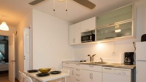 Une cuisine compacte avec des meubles blancs, un four à micro-ondes, une machine à café et un lave-vaisselle.