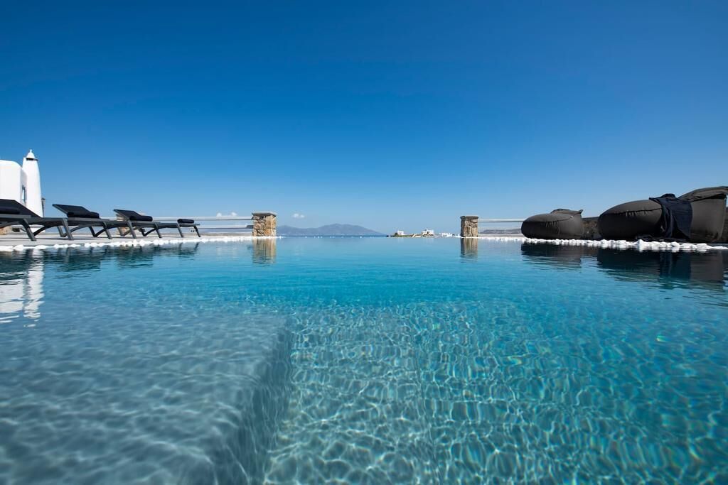 Een buitenzwembad, ligstoelen bij het zwembad