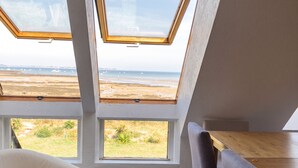 Une chambre avec vue sur la plage, une table en bois et une chaise blanche.