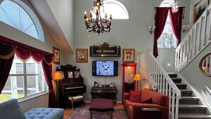 A living room with a grand piano, a television, a chandelier, and a staircase. - Disney Themed Home! Magic Kingdom Inspired!!  Hidden Mickeys!!! (Davenport)