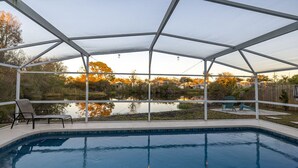 A covered swimming pool with a view of a lake and houses in the background. - Disney Themed Home! Magic Kingdom Inspired!!  Hidden Mickeys!!! (Davenport)