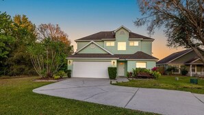 A two-story house with a garage, surrounded by a well-maintained lawn and various plants. - Disney Themed Home! Magic Kingdom Inspired!!  Hidden Mickeys!!! (Davenport)
