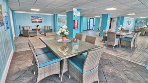 Amplio espacio interior con mobiliario de mimbre, una mesa de vidrio y una pared azul.