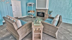 Una sala de estar acogedora con muebles de mimbre, una chimenea y una estantería.