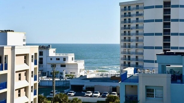 Een hotel aan de kust met meerdere verdiepingen, balkons en uitzicht op zee.