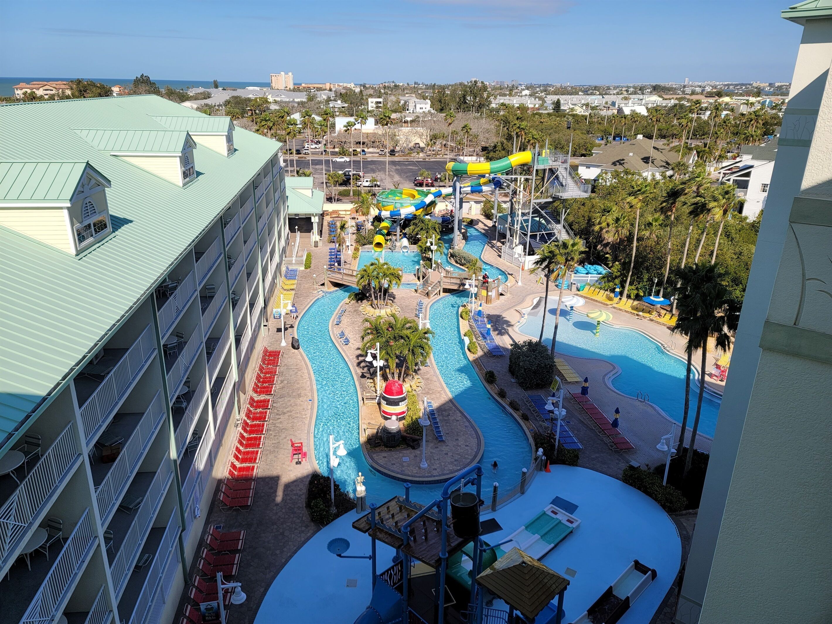 A resort with a large pool area, multiple water slides, and a view of the ocean.
