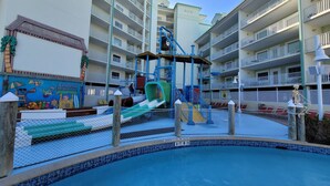 Un espace piscine équipé d’un toboggan, d’une aire de jeux pour enfants et d’un panneau indiquant une profondeur de 3 pieds.