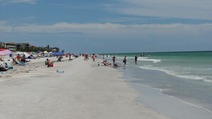 Une plage avec des parasols et des gens.