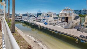 Un port de plaisance avec plusieurs bateaux amarrés, une passerelle en bois et un ciel dégagé.
