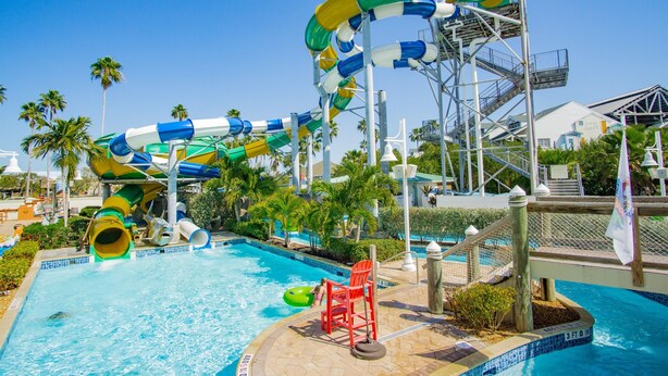 Un parque acuático con una piscina grande, un tobogán de agua y una silla para socorrista.