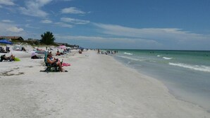 A beach with people sunbathing and swimming, umbrellas, and beach chairs. - Waterfront, Harbourside, Water Park, Beach, #5515 (Indian Rocks Beach)