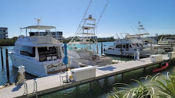 A marina with several yachts docked, a wooden pier, and a small red boat.