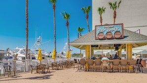 A beachside restaurant with outdoor seating, palm trees, and boats in the background. - Waterfront, Harbourside, Water Park, Beach, #8815 (Indian Rocks Beach)