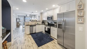 Una cocina moderna con armarios blancos, electrodomésticos de acero inoxidable y un tapete azul.