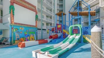 A children's play area with slides and a pool, surrounded by a multi-level building with balconies.