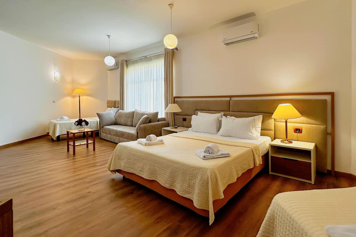 Ein Hotelzimmer mit Bett, Sofa, kleinem Tisch, Lampe und Klimaanlage.