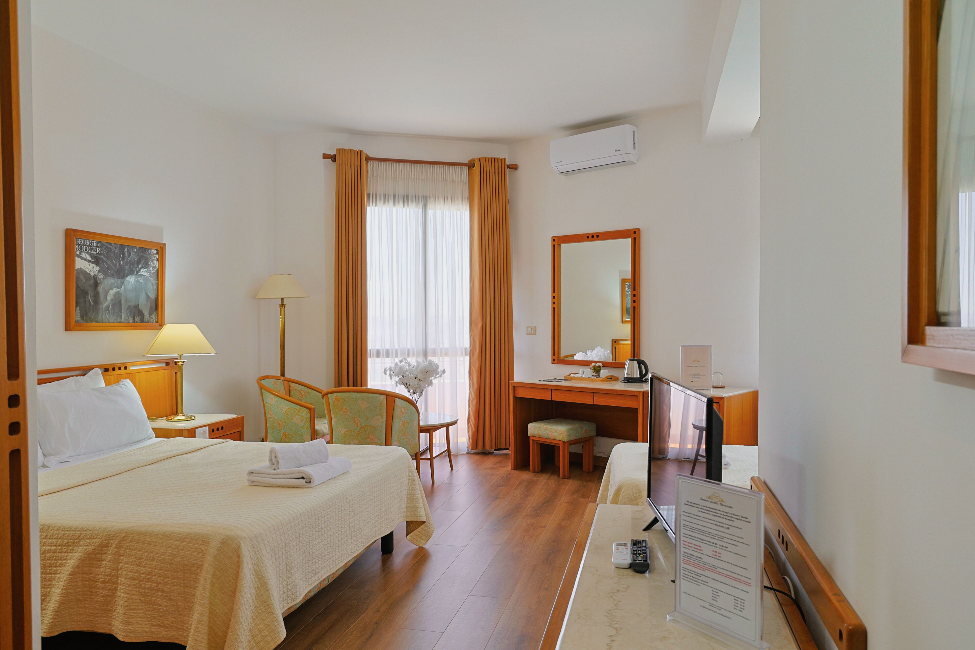 A hotel room with a bed, desk, chair, and a large mirror.