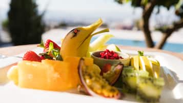 Un assortiment de fruits frais présentés sur un plateau, accompagné d’un petit bol de graines de grenade.