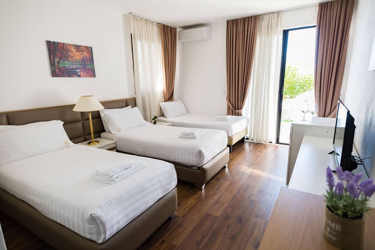 Ein Hotelzimmer mit zwei Betten, einem Schreibtisch, einem Fernseher und einem Fenster mit Vorhängen.