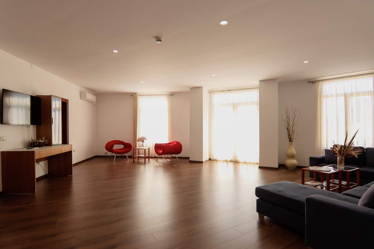 Ein modernes Wohnzimmer mit Holzboden, einer Couch, einem Couchtisch, einem Fernseher und einem Schreibtisch mit Stuhl.